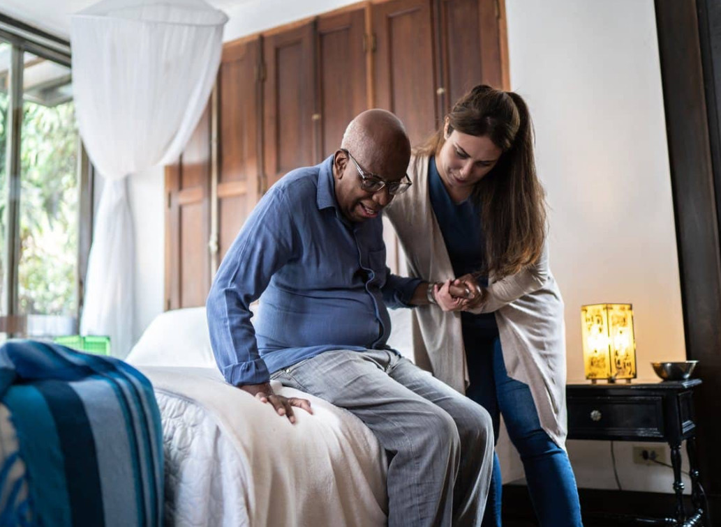 Assistante de vie aidant une personne à se relever à domicile